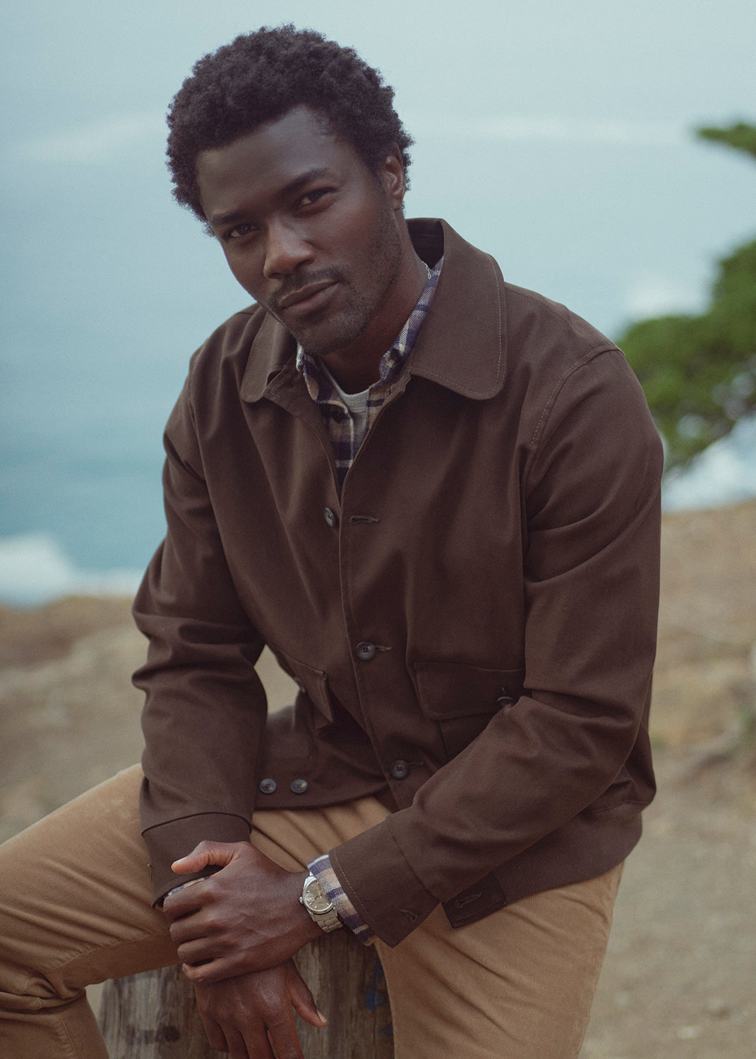 A man wearing Gage in Catalina, Utility Jacket in Dark Olive, Shigoto Shirt in Rambler Plaid, and Everyday Short Sleeve Tee in Heather Grey