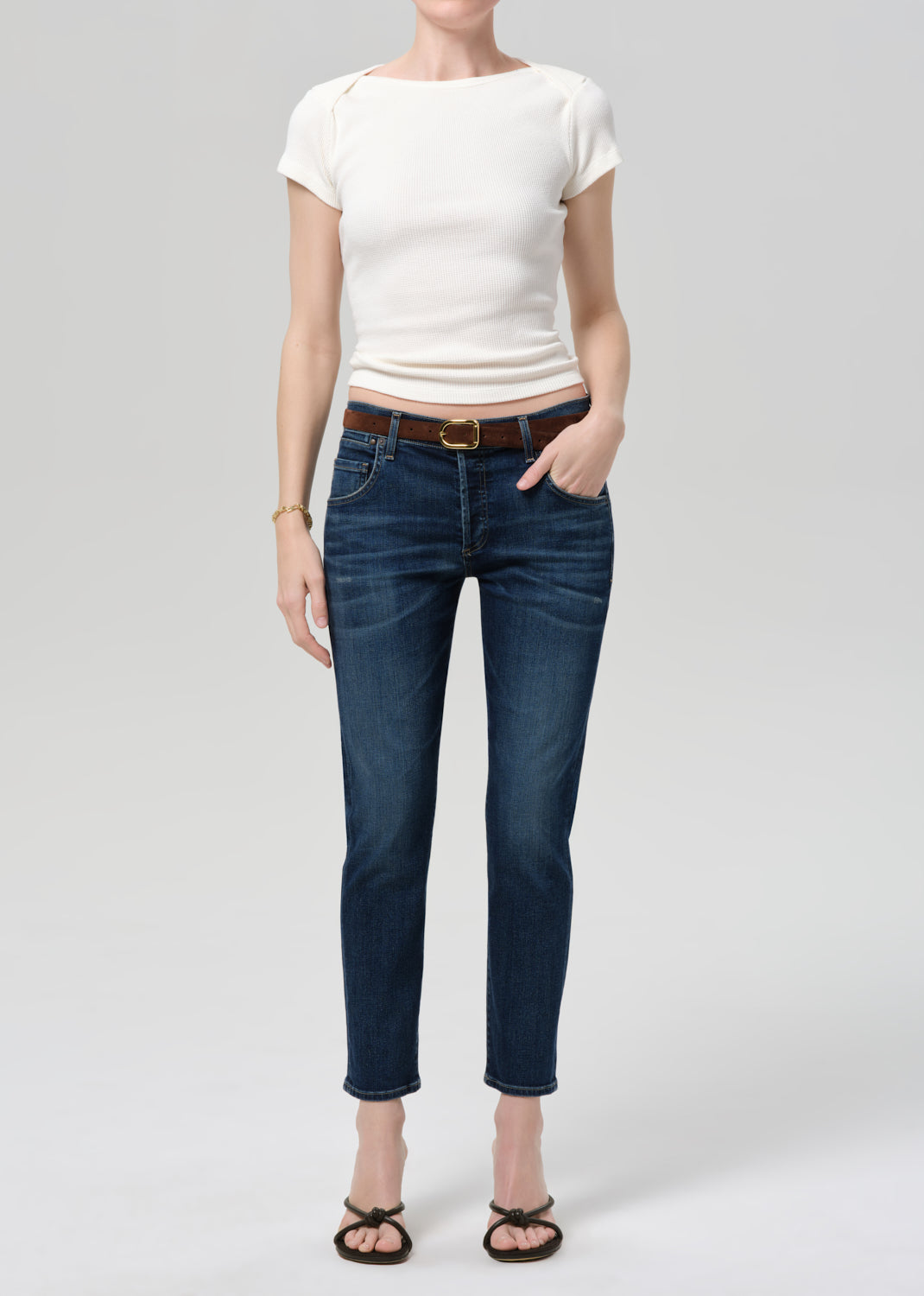 Person wearing a white top and blue jeans on a plain background