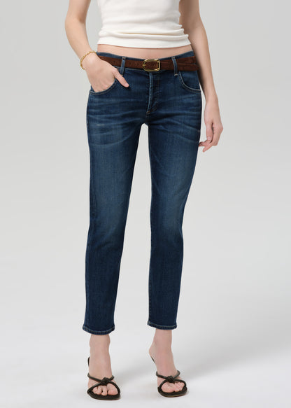 Person wearing blue jeans and a white top on a plain background