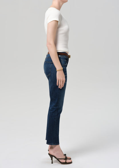 Person wearing blue jeans and a white top on a plain background