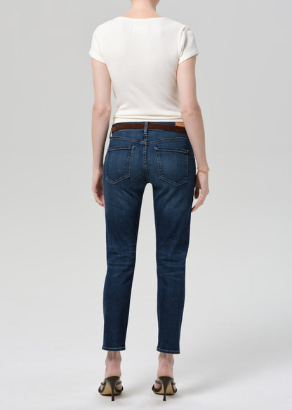 Person wearing blue jeans and a white top on a plain background