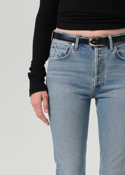 Close up of person wearing a black belt and blue pants on a grey background