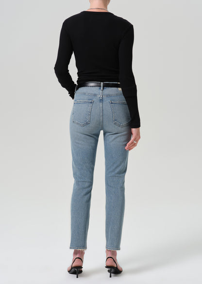 Person wearing black long sleeve top with blue pants on a grey background