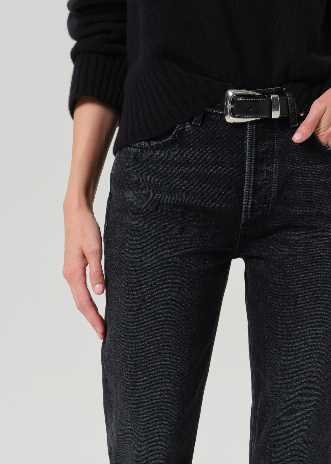 Close up of black pants and black belt on a grey background