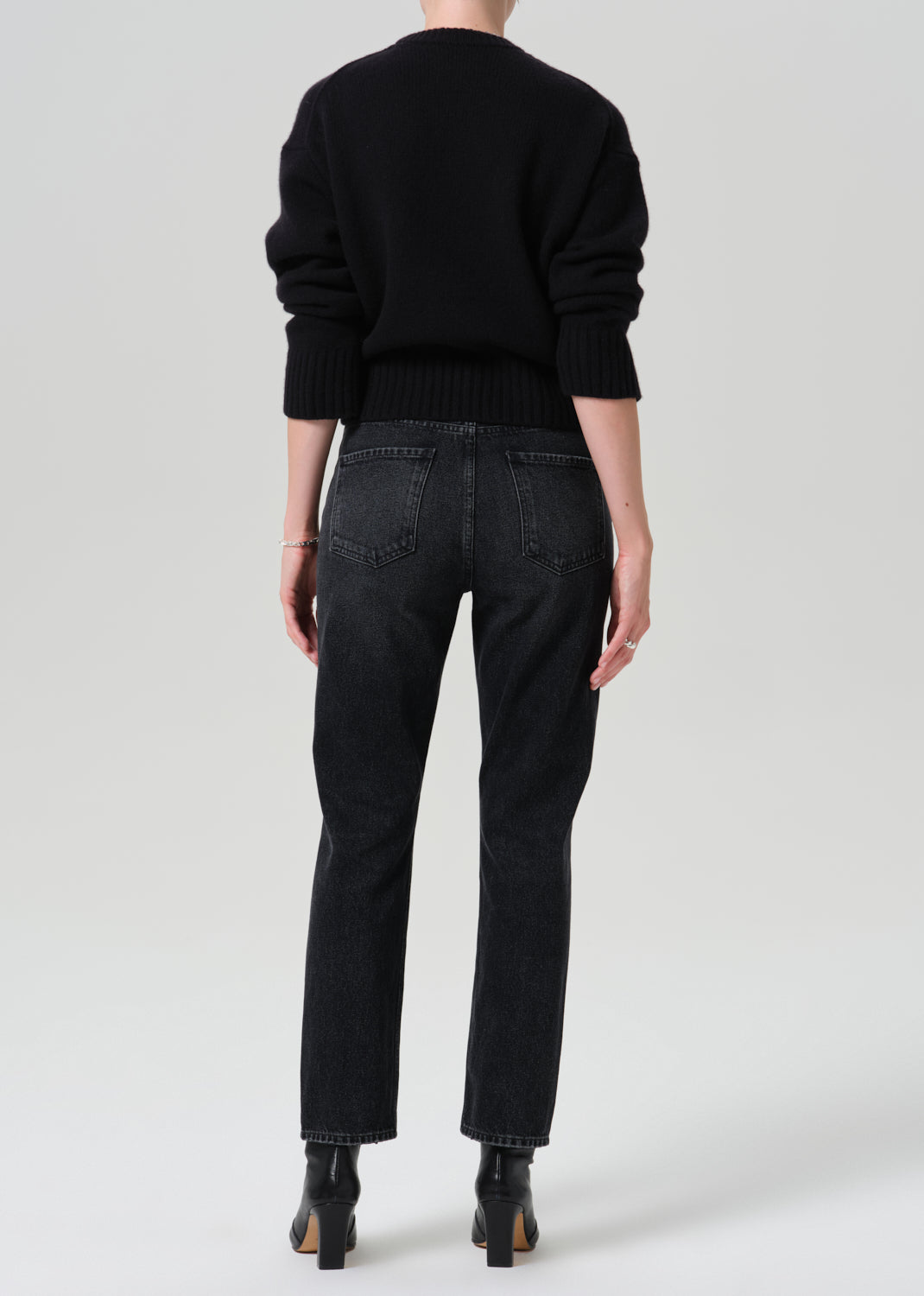 Person wearing a black outfit on a grey background