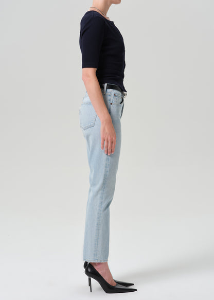 Person wearing navy cardigan with light blue pants on a grey background