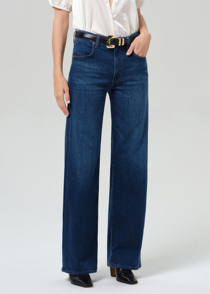 Person wearing blue jeans with a white shirt on a light gray background