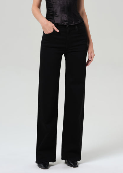 Person wearing a black corset top and black pants on a grey background