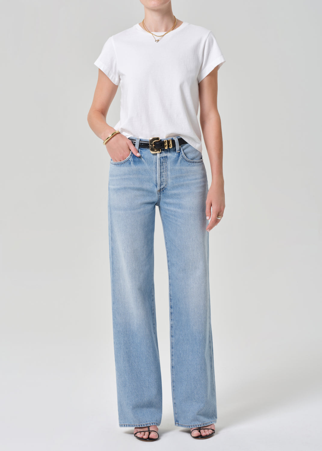 Person wearing a white t-shirt and light blue jeans on a plain background