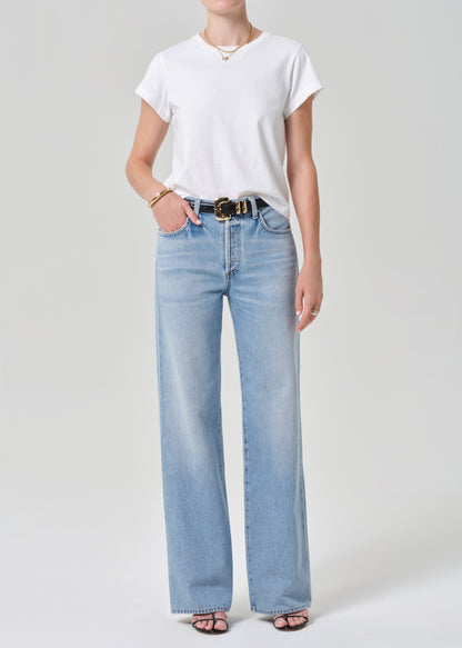 Person wearing a white t-shirt and light blue jeans on a plain background