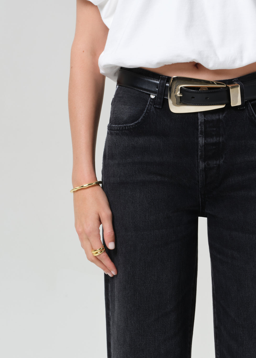 Person wearing a white top and black jeans on a plain background