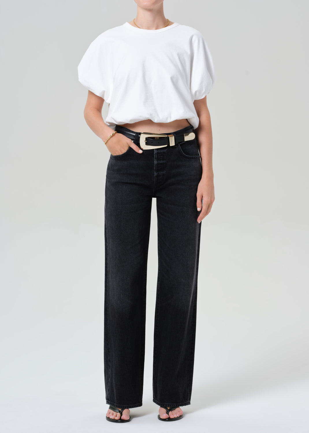 Person wearing a white top and black jeans on a plain background