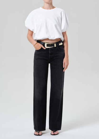 Person wearing a white top and black jeans on a plain background