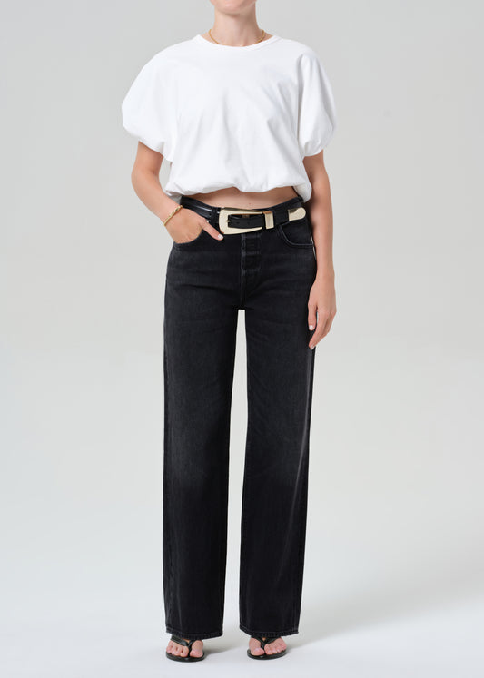 Person wearing a white top and black jeans on a plain background