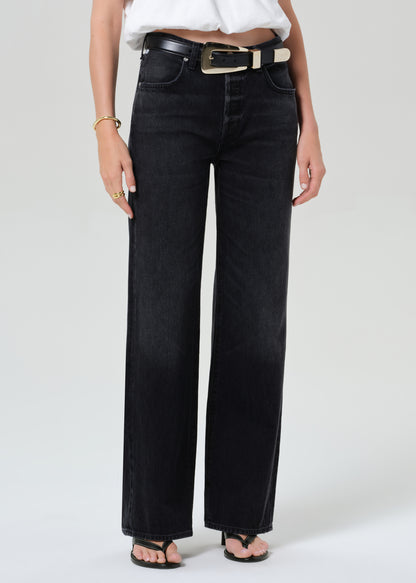 Person wearing a white top and black jeans on a plain background