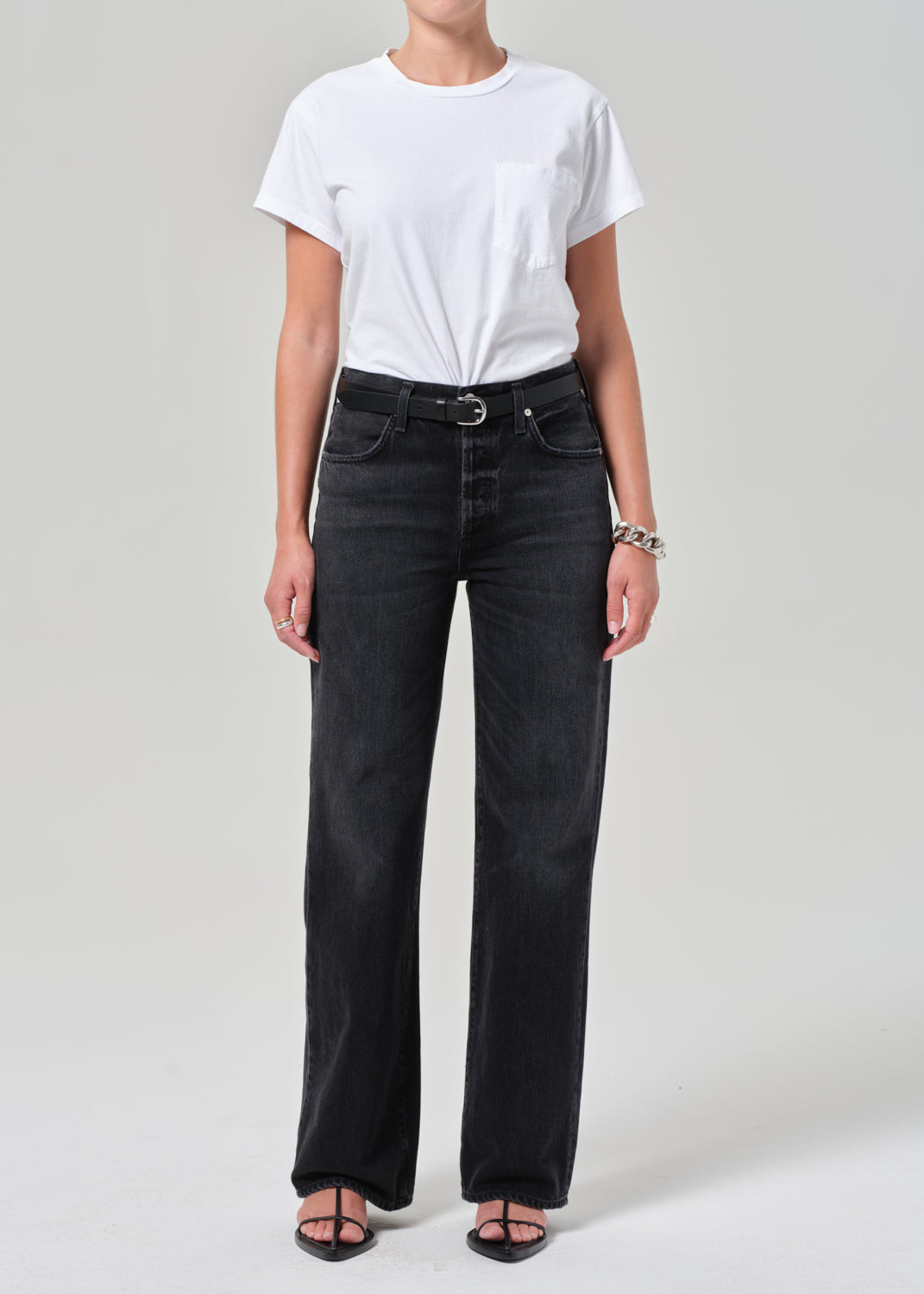 Person wearing a white t-shirt and black jeans on a plain background