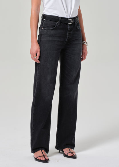 Person wearing black jeans and a white top on a plain background