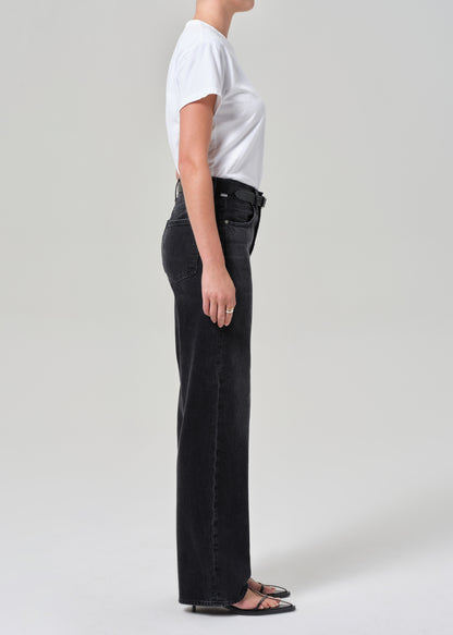 Person wearing black jeans and a white shirt on a plain background