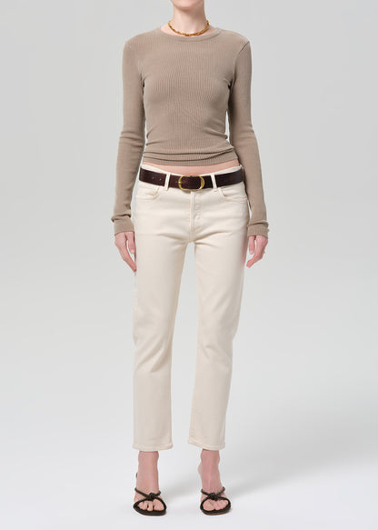Person wearing a brown ribbed top and off-white jeans on a grey background