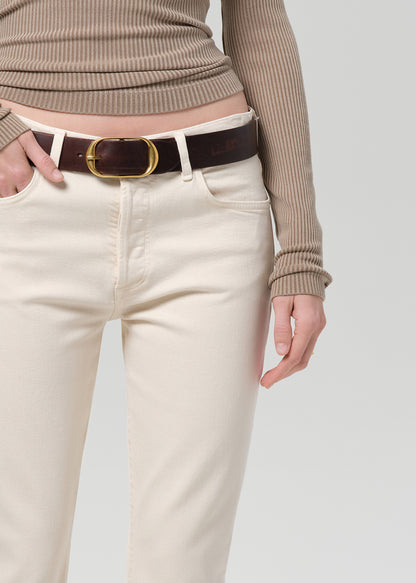 Person wearing a brown ribbed top and off-white jeans on a grey background