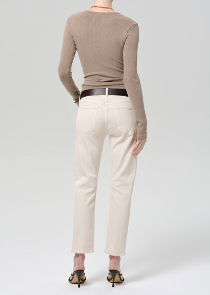 Person wearing a brown ribbed top and off-white jeans on a grey background