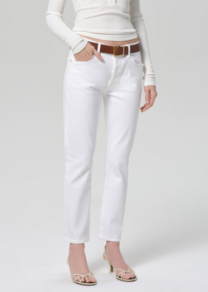 Person wearing a white long-sleeve top and white jeans with a brown belt on a light gray background