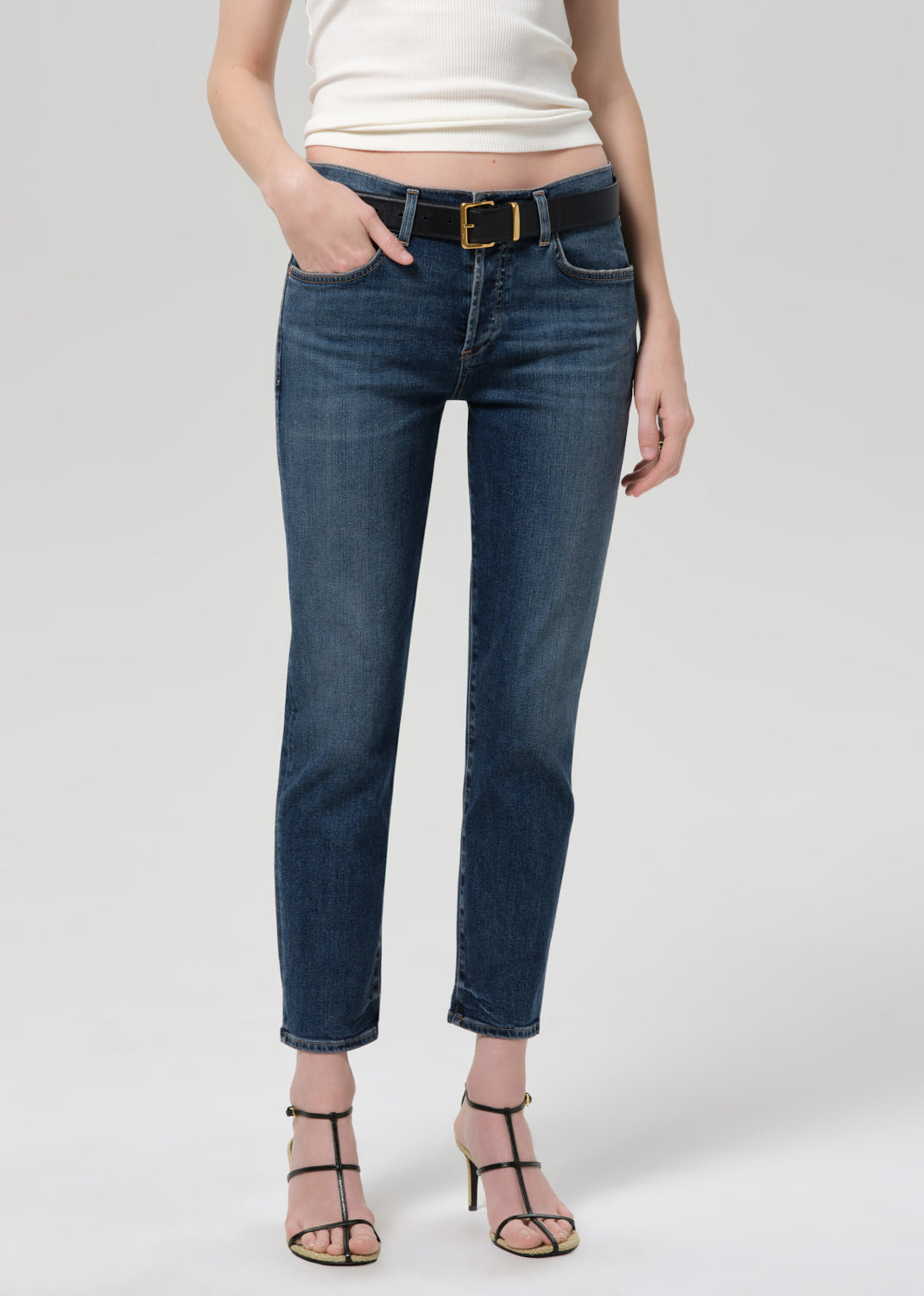 Person wearing blue jeans and a white top on a plain background