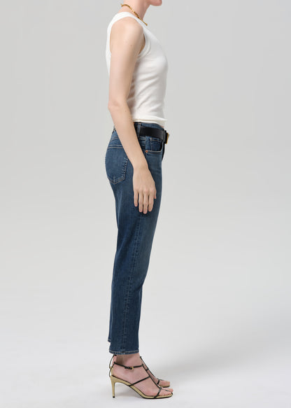 Person wearing blue jeans and a white top on a plain background