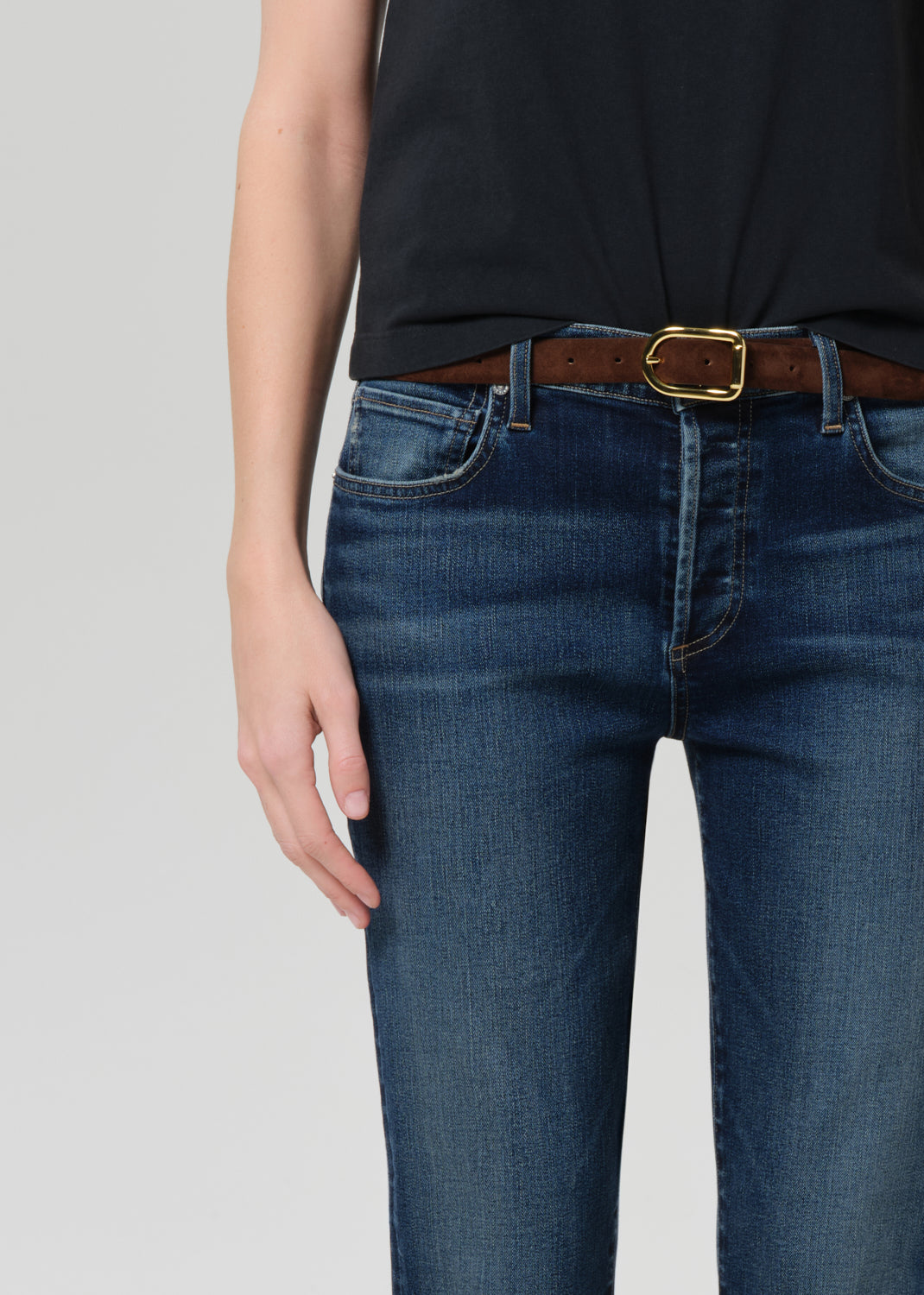 Person wearing a black t-shirt and blue jeans on a grey background