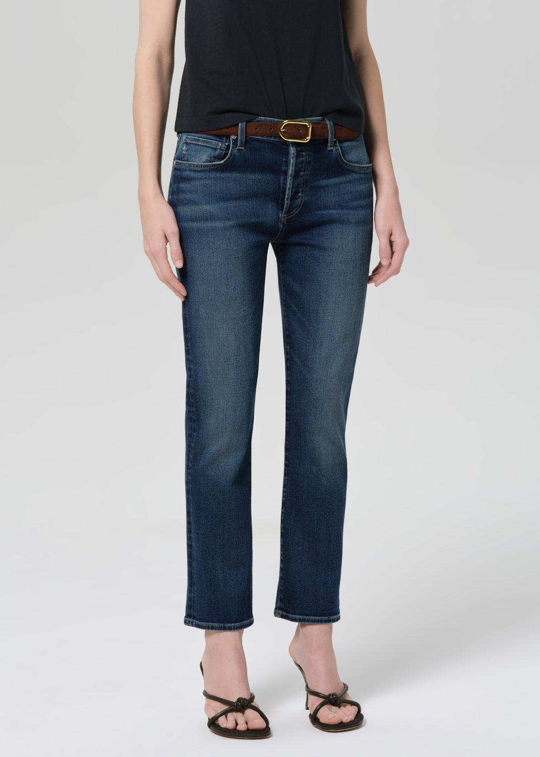 Person wearing a black t-shirt and blue jeans on a grey background