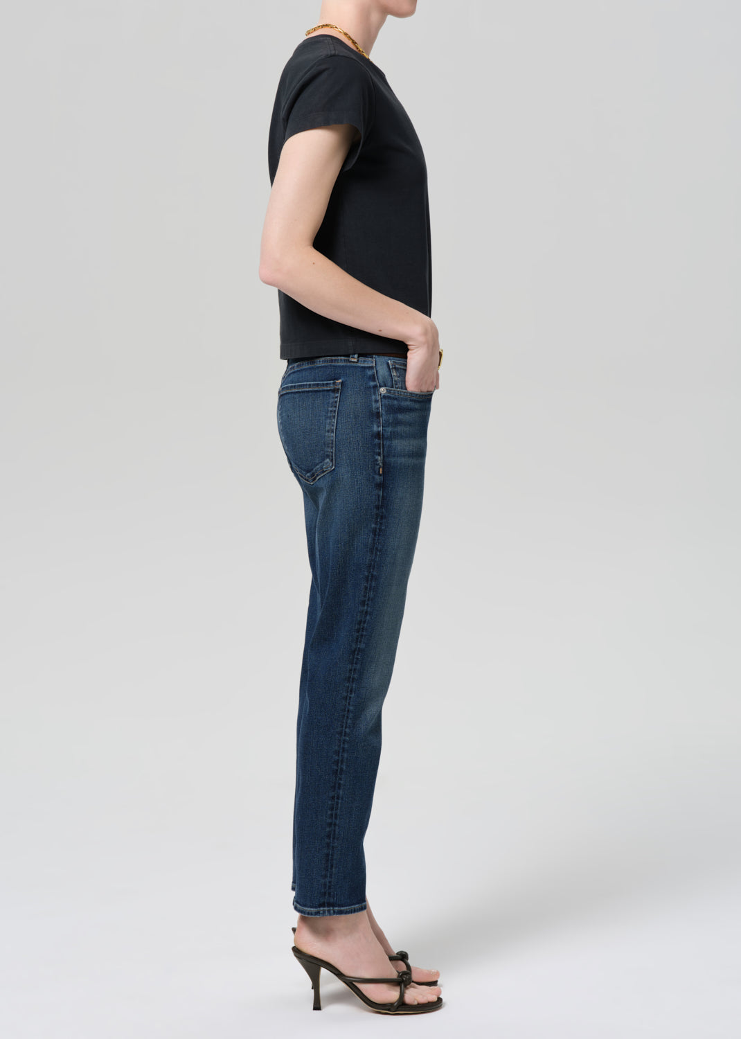 Person wearing a black t-shirt and blue jeans on a grey background