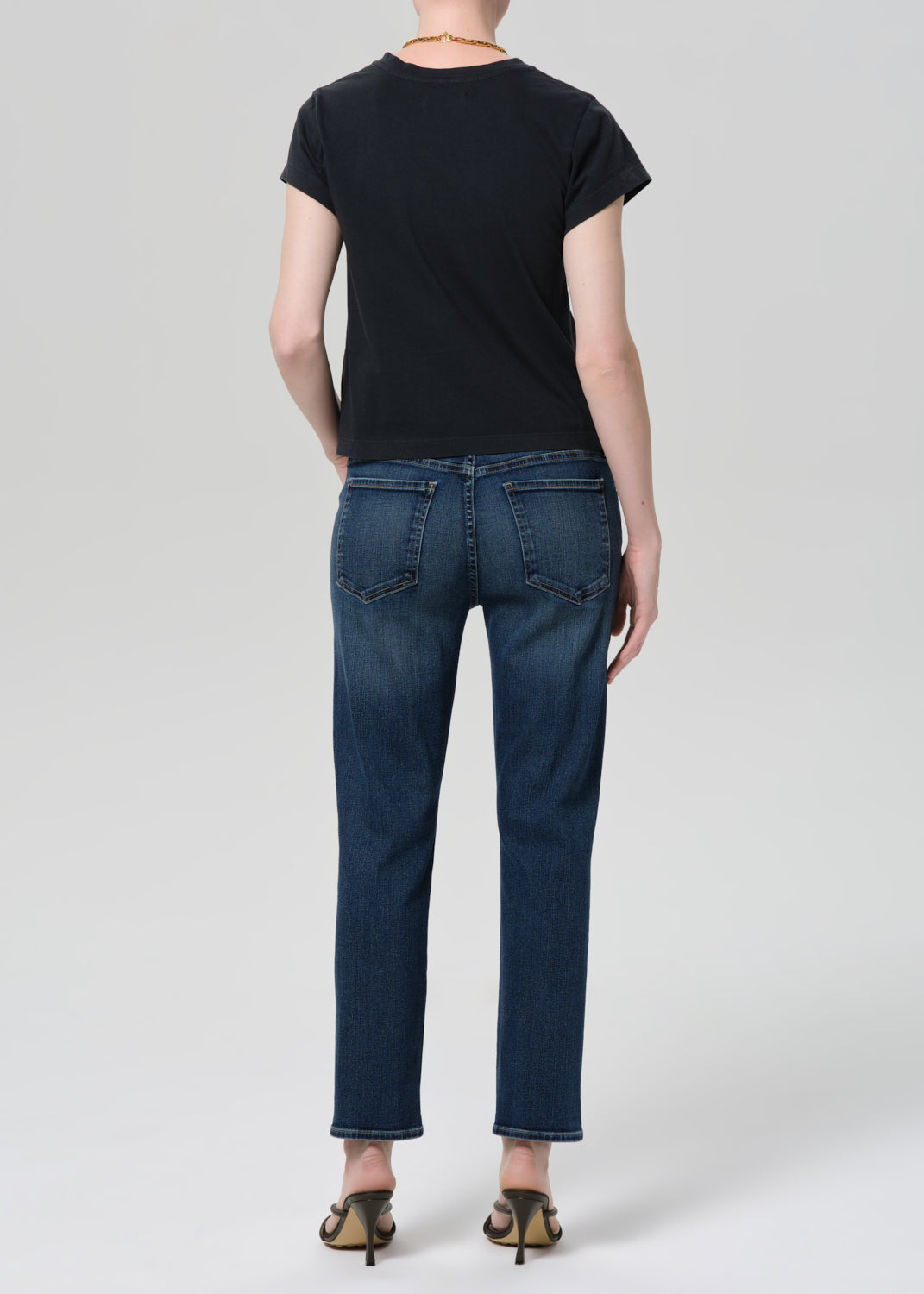 Person wearing a black t-shirt and blue jeans on a grey background