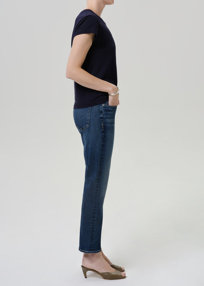 Person wearing dark blue straight leg cropped jeans with a navy short sleeve crewneck t-shirt and heels, side full body view on a grey background.
