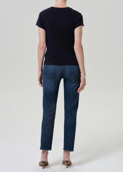 Person wearing dark blue straight leg cropped jeans with a navy short sleeve crewneck t-shirt and heels, back full body view on a grey background.