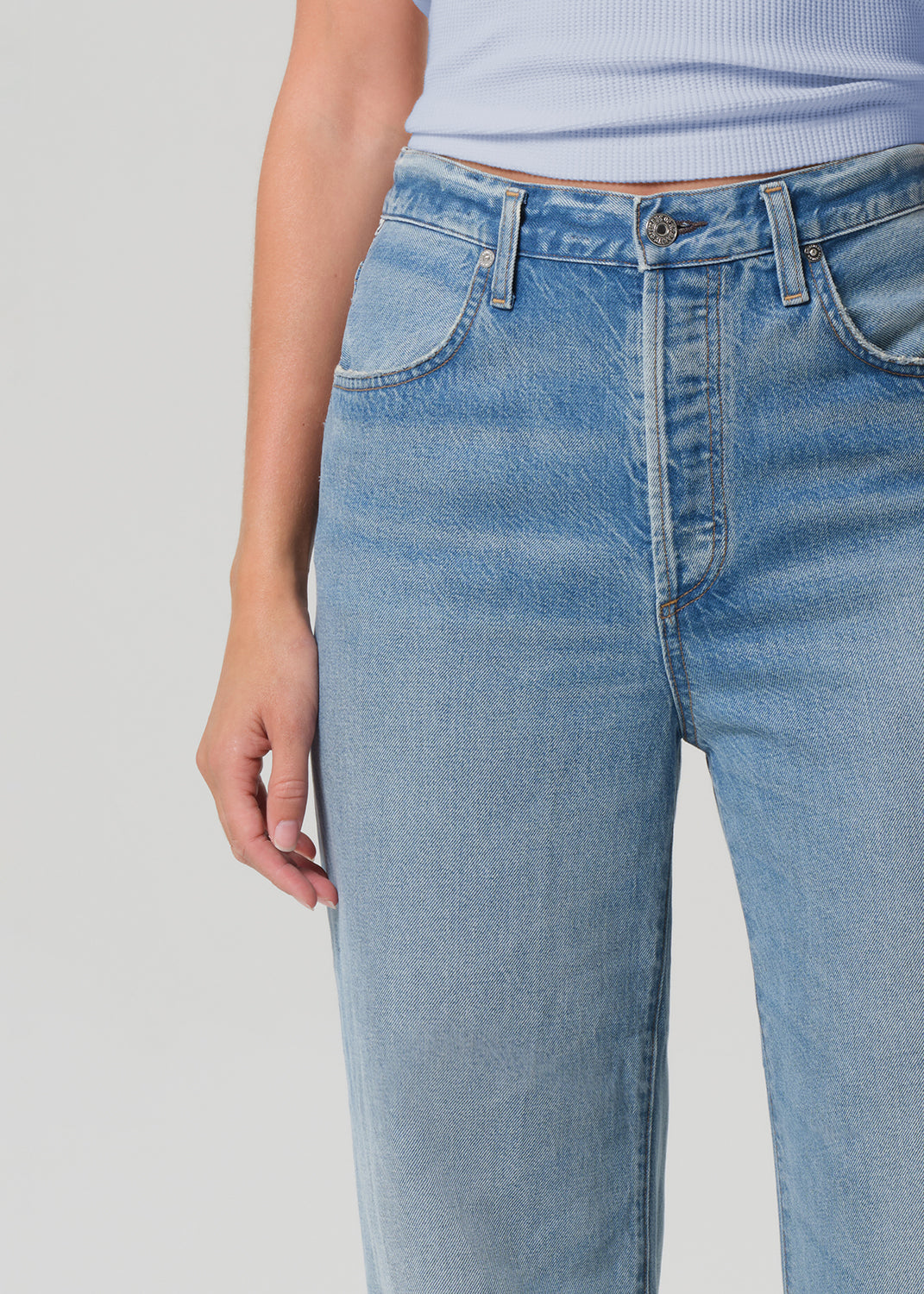 Light blue jeans worn by a person on a gray background