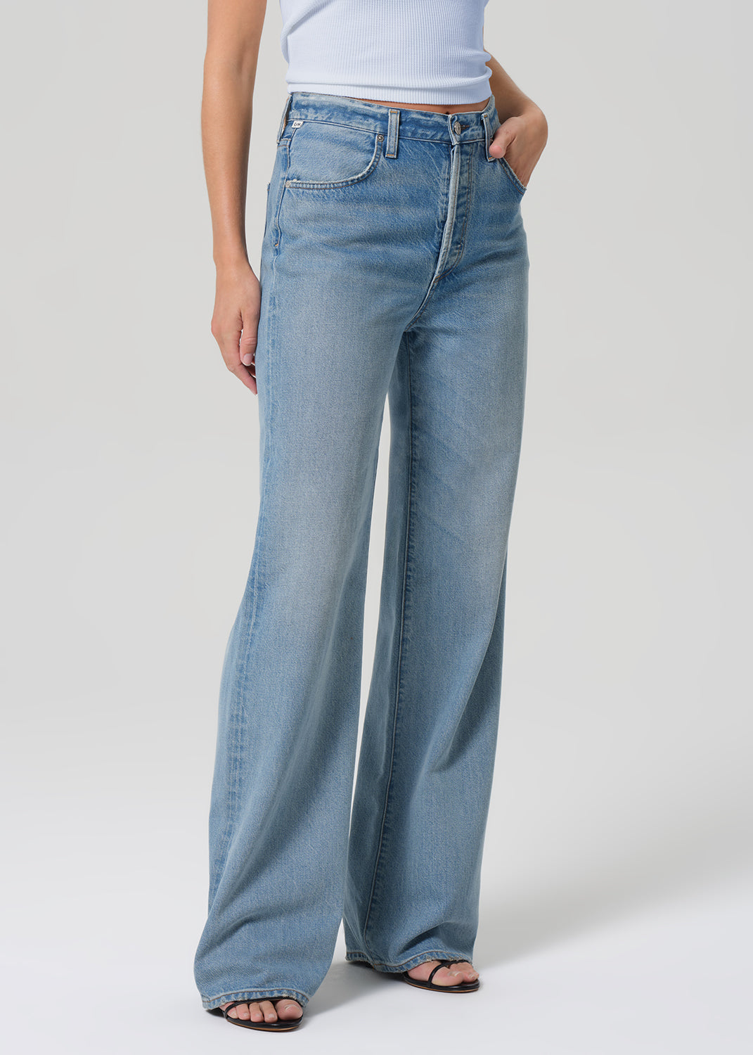 Person wearing light blue wide-leg jeans on a plain background