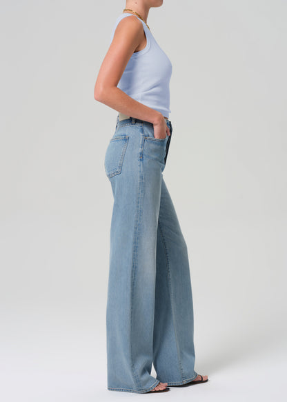 Person wearing light blue jeans and a white top on a plain background