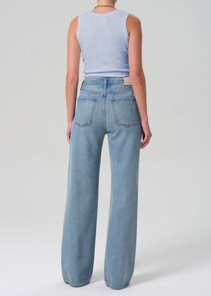 Person wearing light blue jeans and a sleeveless top on a white background