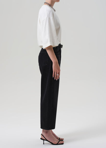 Person wearing a white tee and black pants on a plain background