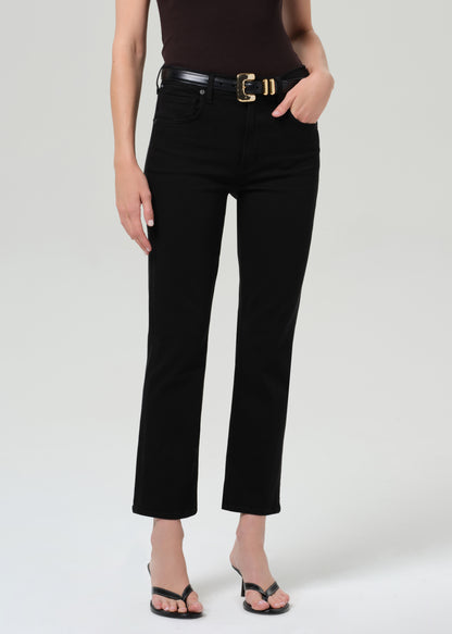 Person wearing a brown t-shirt and black jean with a belt on a grey background