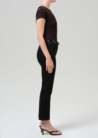 Person wearing a brown t-shirt and black jean with a belt on a grey background