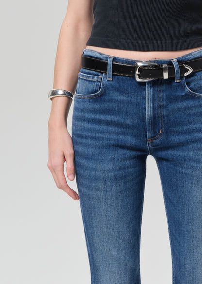 Person wearing a black sleeveless top and blue jeans on a plain background