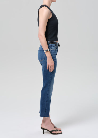 Person wearing a black sleeveless top and blue jeans on a plain background