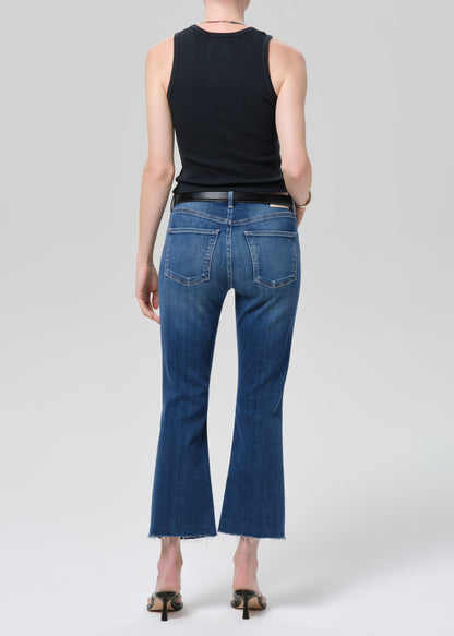 Person wearing a black sleeveless top and blue jeans on a plain background