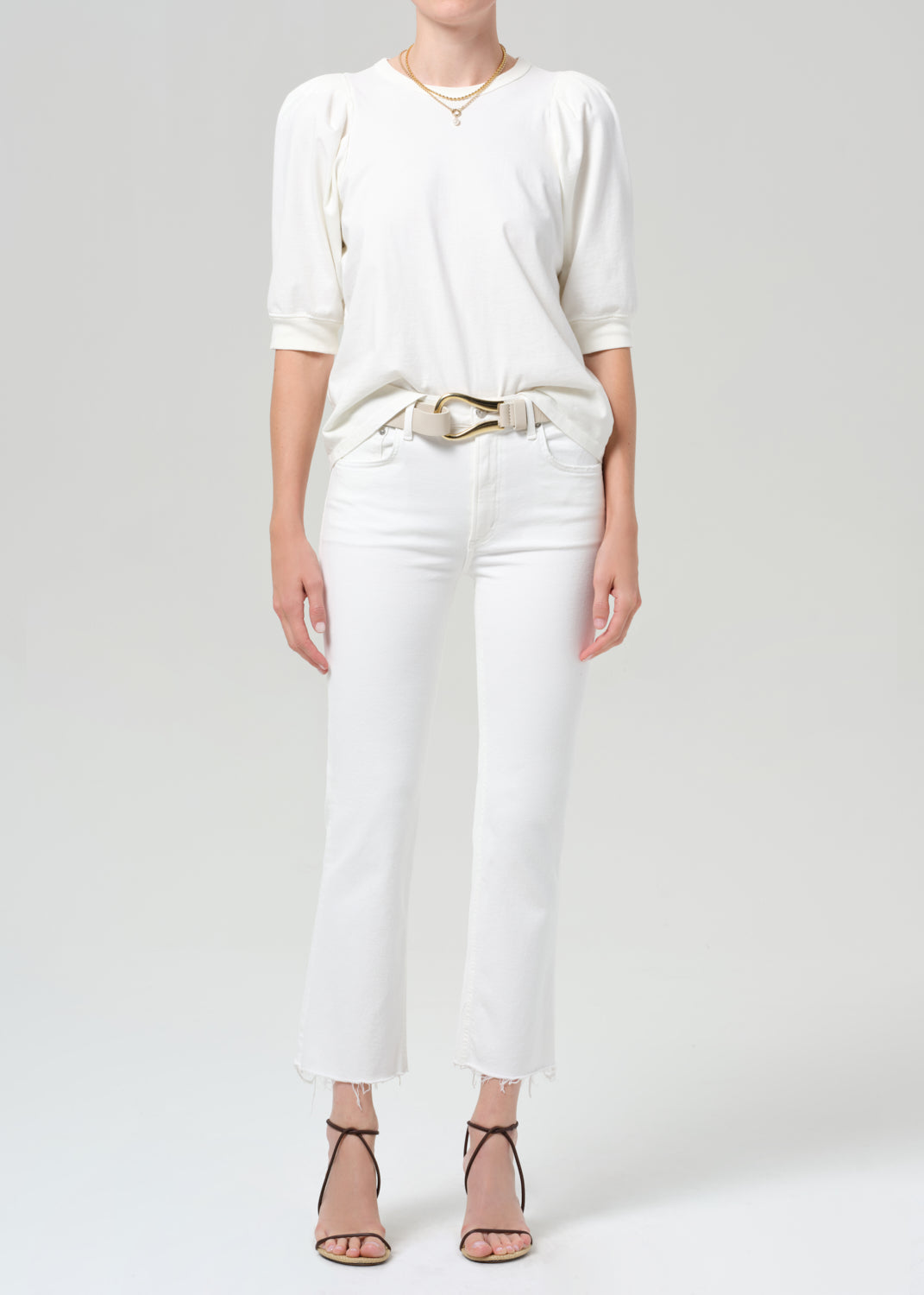 Person wearing a white shirt with white jean on a plain background