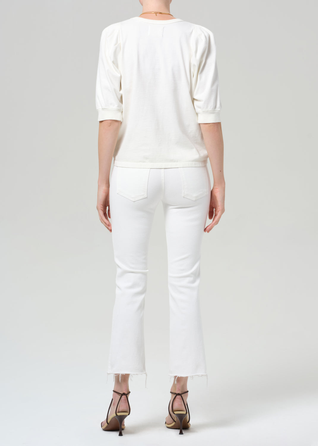 Person wearing a white shirt with white jean on a plain background