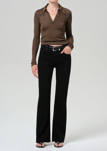 Person wearing a brown long-sleeve polo and black jeans on a grey background