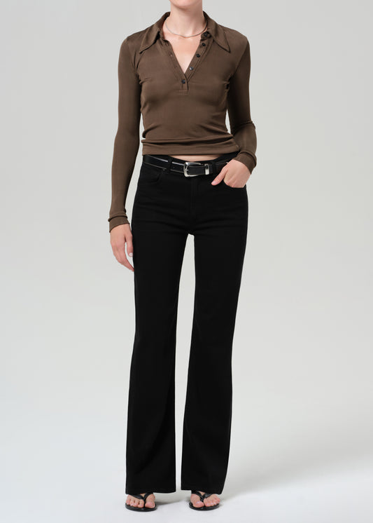 Person wearing a brown long-sleeve polo and black jeans on a grey background