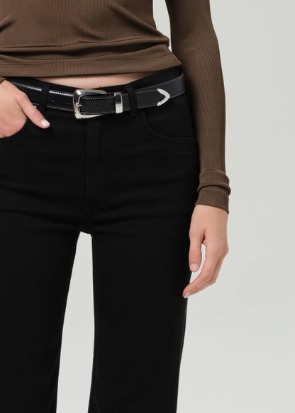 Person wearing a brown long-sleeve polo and black jeans on a grey background