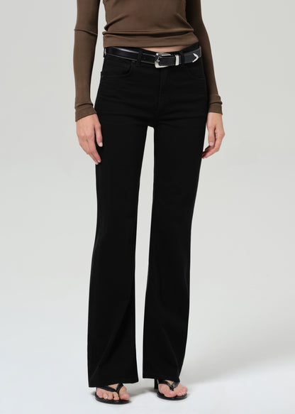 Person wearing a brown long-sleeve polo and black jeans on a grey background